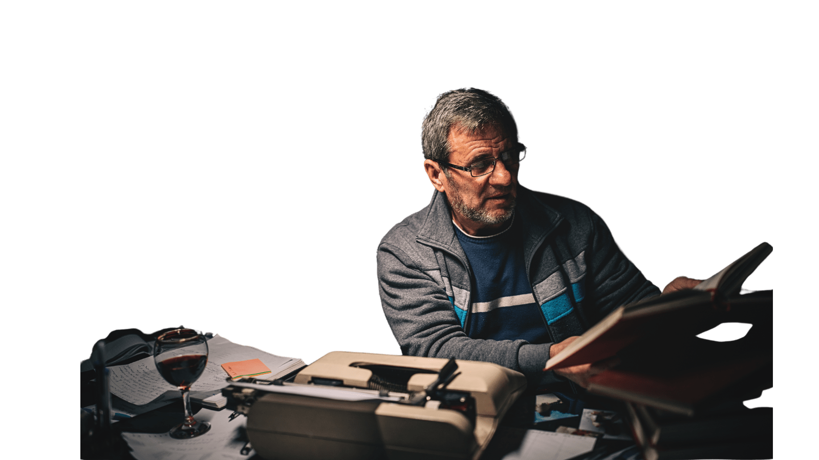 A man sitting at a desk with a laptop and a book.